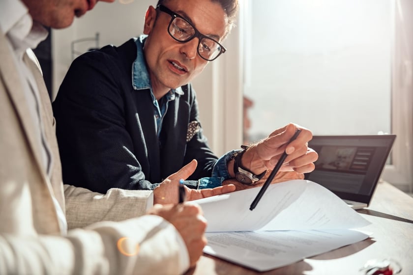 two people sitting at a table going over paperwork